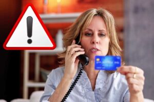 donna al telefono con carta di credito e segnale attenzione