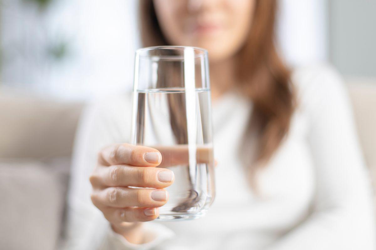 donna con bicchiere di acqua in mano