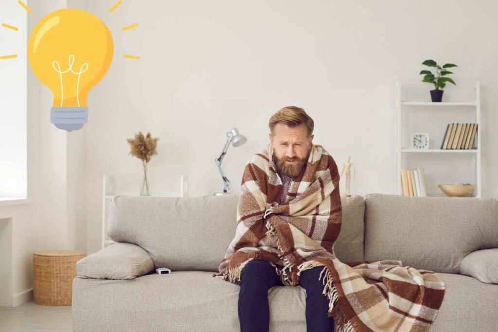 uomo con coperta in casa e lampadina