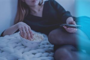 Ragazza con un telecomando e i pop-corn